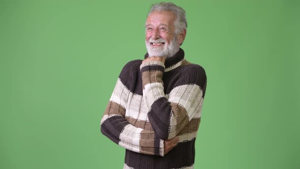 Handsome Senior Bearded Man Wearing Warm Clothing Against Green Background