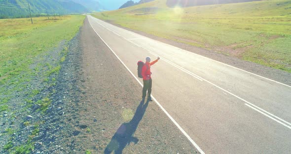 Flight Over Hitchhiker Tourist Walking on Asphalt Road