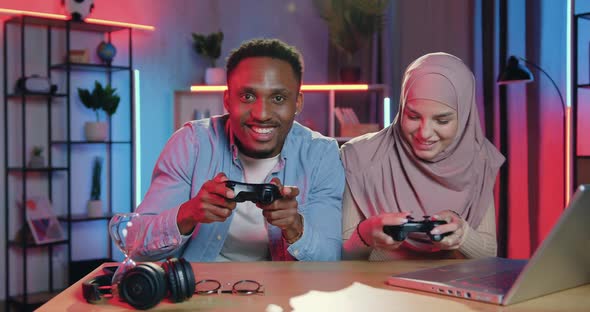 Multiracial Man and Woman Enjoying Video Games and Celebrating Victory with High five