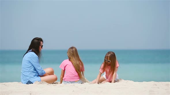 Mother and Little Daughters Making Sand Castle at Tropical Beach
