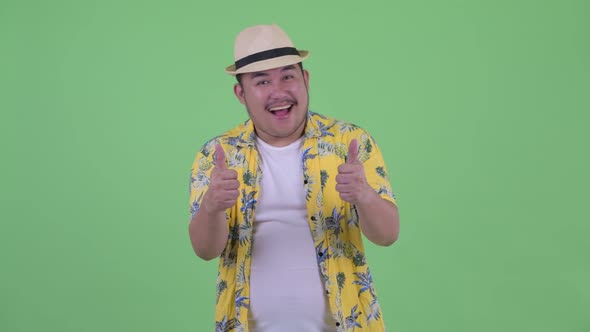 Happy Young Overweight Asian Tourist Man Giving Thumbs Up and Looking Excited