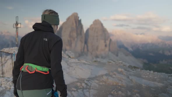 A person with climbing gear walking in front of the famous three peaks - tre cime - Dolomites.