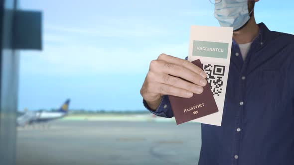 Unidentified Man Wearing a Face Mask and Holding a Passport and a Green Pass Meaningless QR Code
