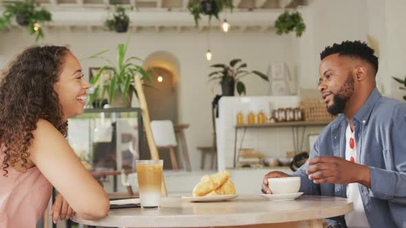Happy diverse couple spending time together at cafe, drinking coffee and talking