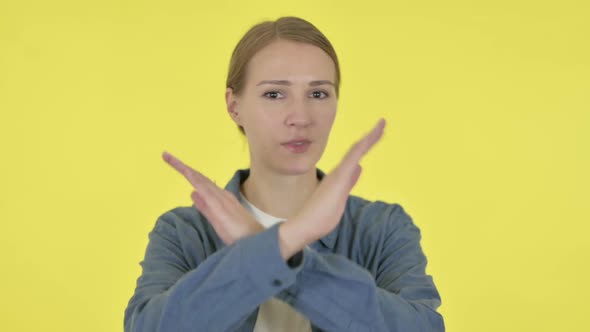Young Woman Showing No Sign By Arm Gesture on Yellow Background