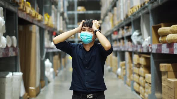 stressed male manager with medical mask in the warehouse store during coronavirus pandemic