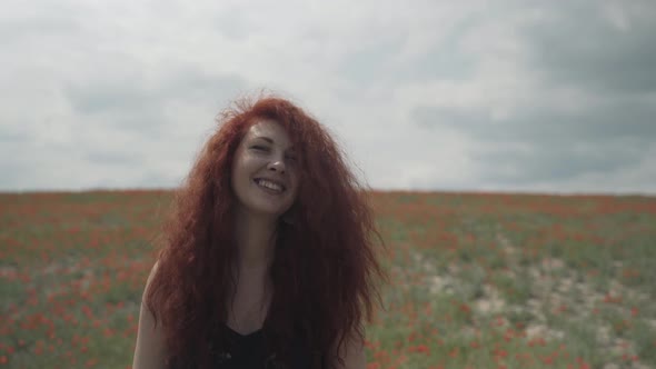 Beautiful Woman with Freckles on Background of Poppy Field