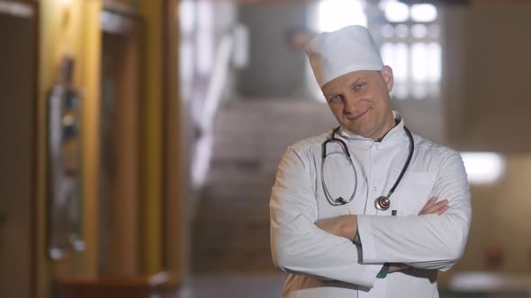 Portrait of a male smiling doctor satisfied with his work in a hospital corridor. The concept of med