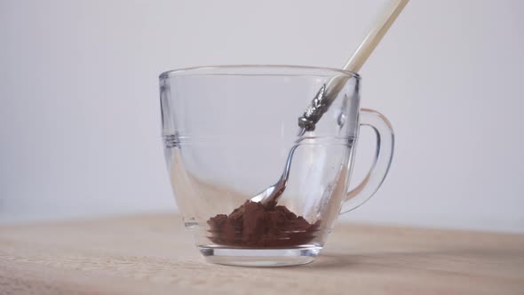 Hand of a young man puts cocoa in a glass cup 