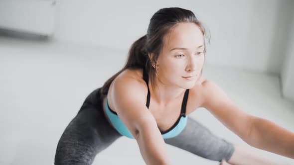 Young Sporty Brunette Girl in Sportswear Does Exercises in Bright Room at Home