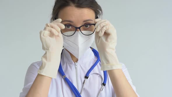 Female Doctor is Putting Off Protective Blue Gloves Isolated on White Background After Some Medical