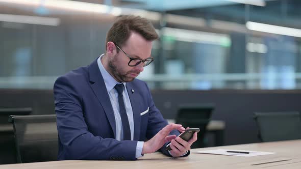 Middle Aged Businessman Using Smartphone at Work