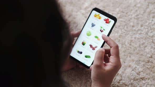 Woman at Home Lying on Carpet in Living Room Using Smartphone for Internet Purchase in Online Store