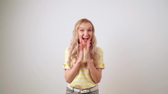 Happy Girl in a Striped Yellow Tshirt on a White Background Claps Her Hands with Joy