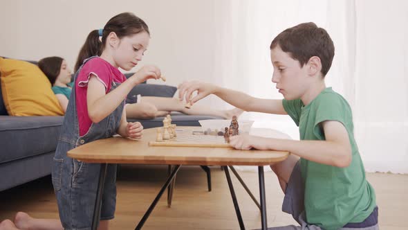Young kids playing Chess on the living room table