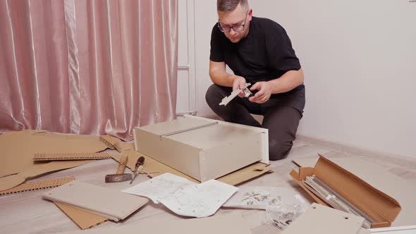 a Young Man on the Floor Collects a Drawer for a Dresser Next to It is a Box and Other Details of a