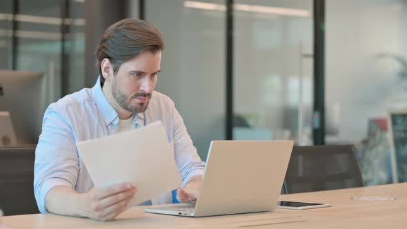 Mature Adult Man with Laptop Having Loss Reading Documents