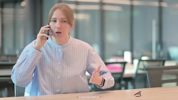 Young Woman Talking Angrily on Smartphone in Office