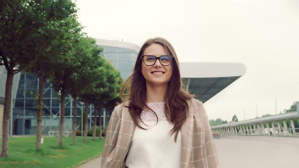 Portrait of a Pretty Young Girl Walking and Looking at the Camera on the Background of the Airport