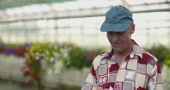 Researcher Examining Potted Plant At Greenhouse