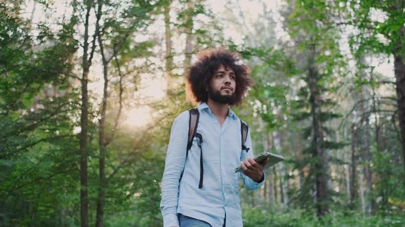 Young Curly Male Environmentalist Walking in Forest
