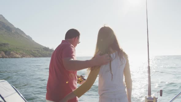 Rear view of a Caucasian man and his teenage daughter fishing on boat