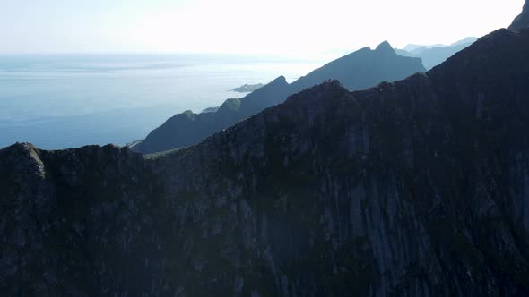 Flying along the chine of a mountain (Reinebringen, Norway) looking at the mountains and the ocean i