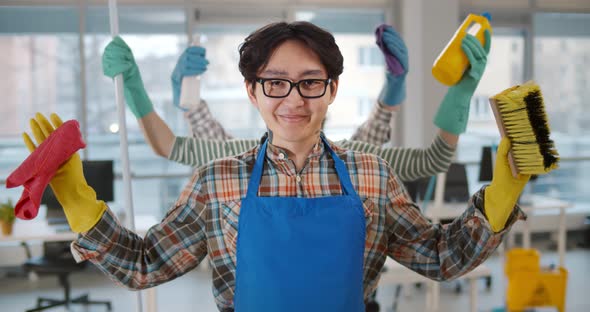 Portrait of Asian Multiarmed Man Janitor Holding Cleaning Equipment and Smiling at Camera