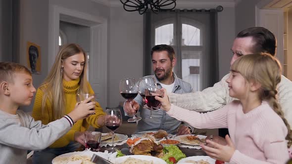 Lovely Family of Different Generation which Sitting Around Festive Dinner and Clinking Glasses