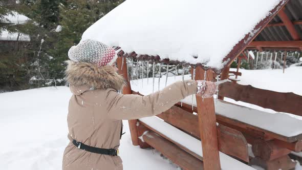 Girl Reaching for Icicles From Arbour Deck in Winter