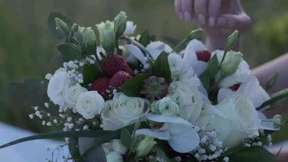 Woman's Hand Touches a Bouquet of White Roses and Strawberries Closeup