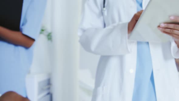 Front view of African american female doctors attaching iv drip on male patient hand in the ward