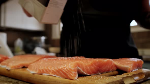 Cooks' Hands Pickle Salmon Fillet Pieces in a Professional Wooden Kitchen Board