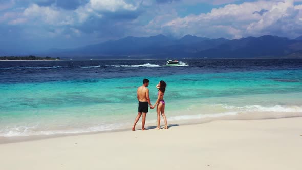 Guy and girl engaged on marine coastline beach holiday by turquoise lagoon and clean sand background