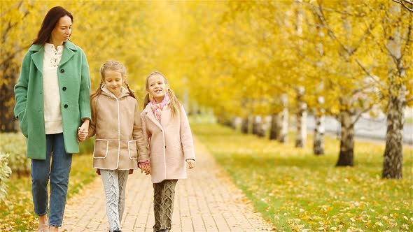 Family of Mother and Kids in Fall. Young Mother and Little Girls Enjoy Warm Autumn