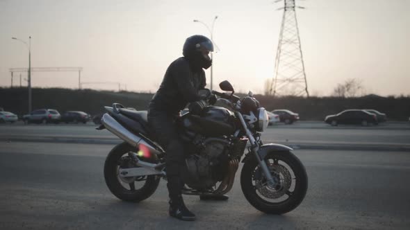 Young Attractive Man Motorcyclist with Black Helmet and Sport Motorcycle on Street