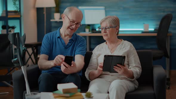 Modern Couple Using Smartphone and Digital Tablet at Home