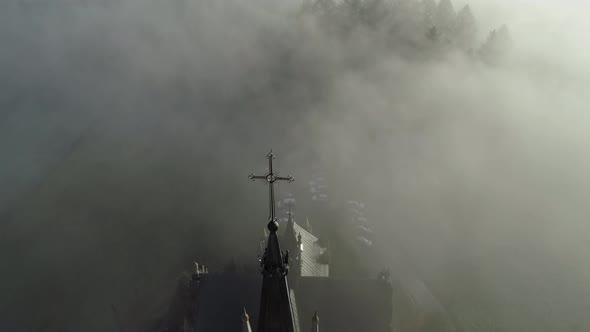 Heavenly scene of neo-Gothic church surrounded by eerie mist in Poland, aerial