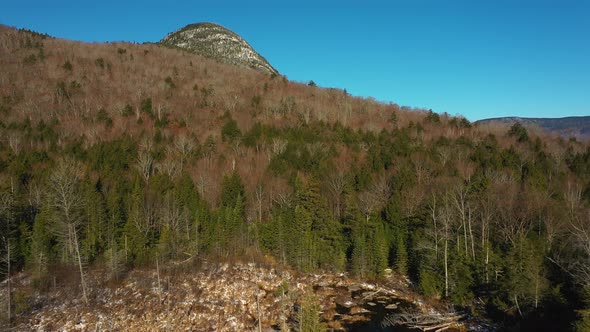 Aerial footage flying over a bog and forest up towards a mountain peak after a late fall snow