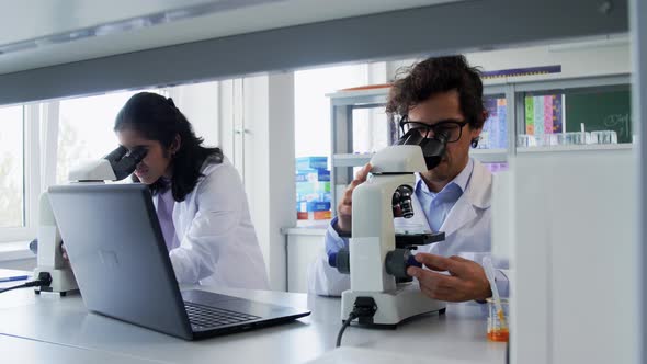 Scientists with Microscopes Working in Laboratory