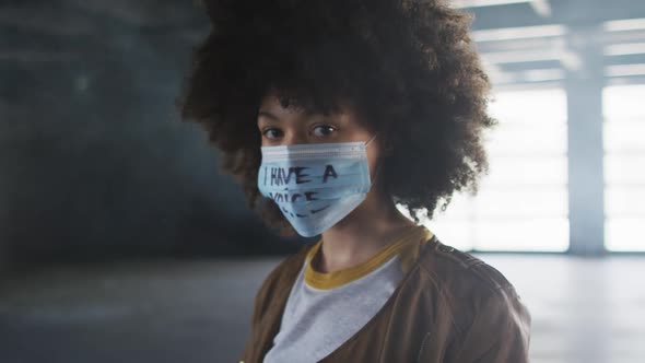 Portrait of african american woman wearing protest face mask in empty parking garage