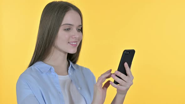 Cheerful Beautiful Woman Using Smartphone, Yellow Background