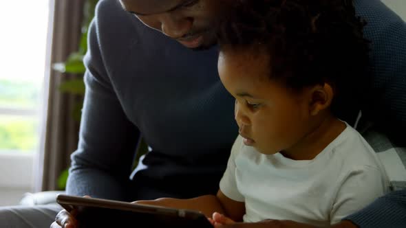 Close-up of young black father and son using digital tablet in a comfortable home 4k