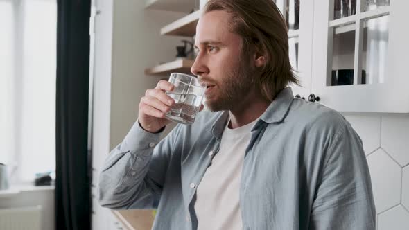 Handsome Male Drink or Take of Mineral Water in Glass in Kitchen in House