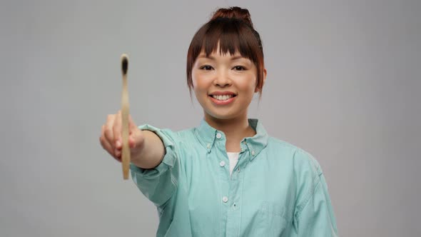 Smiling Asian Woman with Wooden Toothbrush