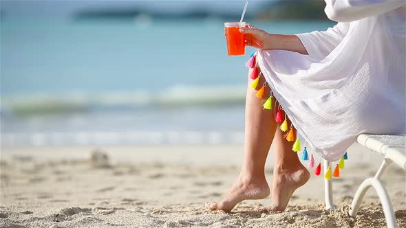 Young Woman with Cocktail Glass on White Beach Sitting on Sunbed. Closeup Tasty Cocktail Background