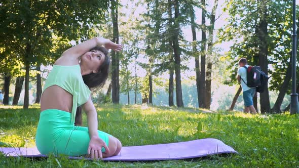 Young European Woman Sportswear Purple Mat Practicing Yoga Pose Park Green Lush Meadow City Park