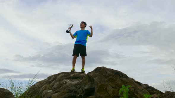 Athlete Holding Trophy On The Top Of Mountain And Cheering