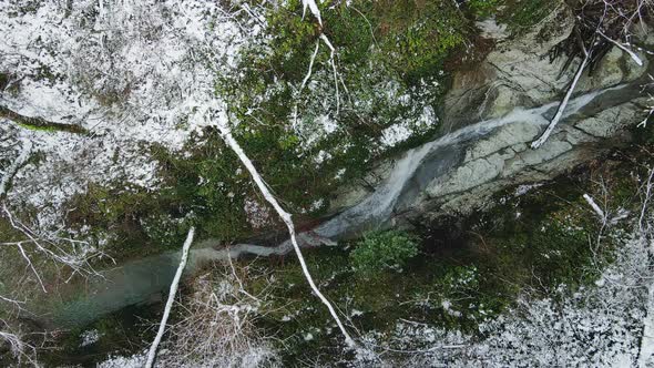 Stream of Water Flowing Among the White Rocks in the Forest in Winter