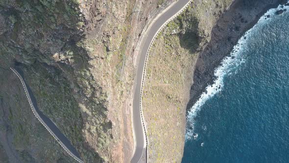 Aerial Drone Footage of an Empty Road Along a Cape with Vertical Overhanging Cliffs Over the Ocean